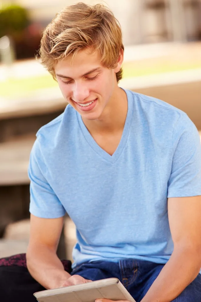 A smiling student looking down at a tablet